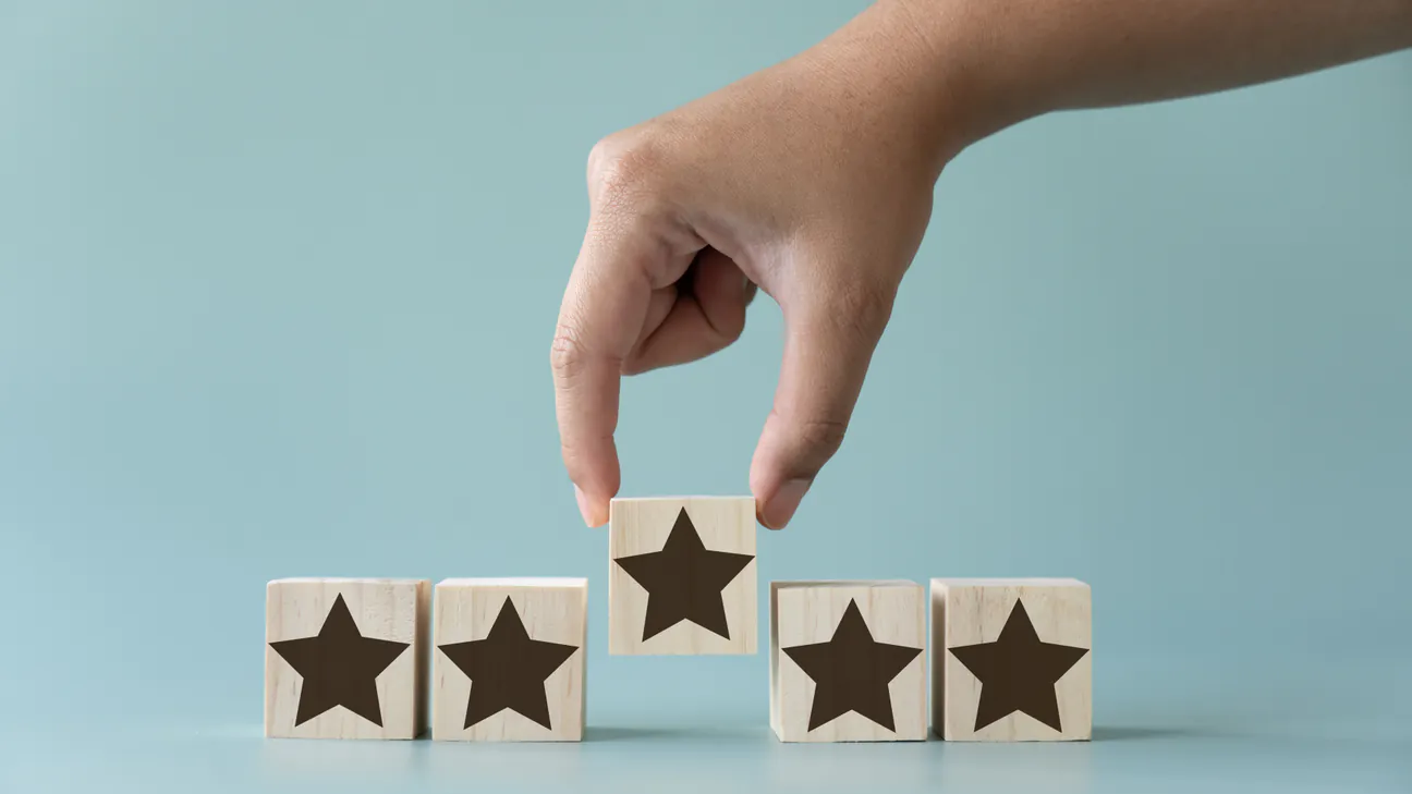 Hand arranging wooden blocks with star ratings
