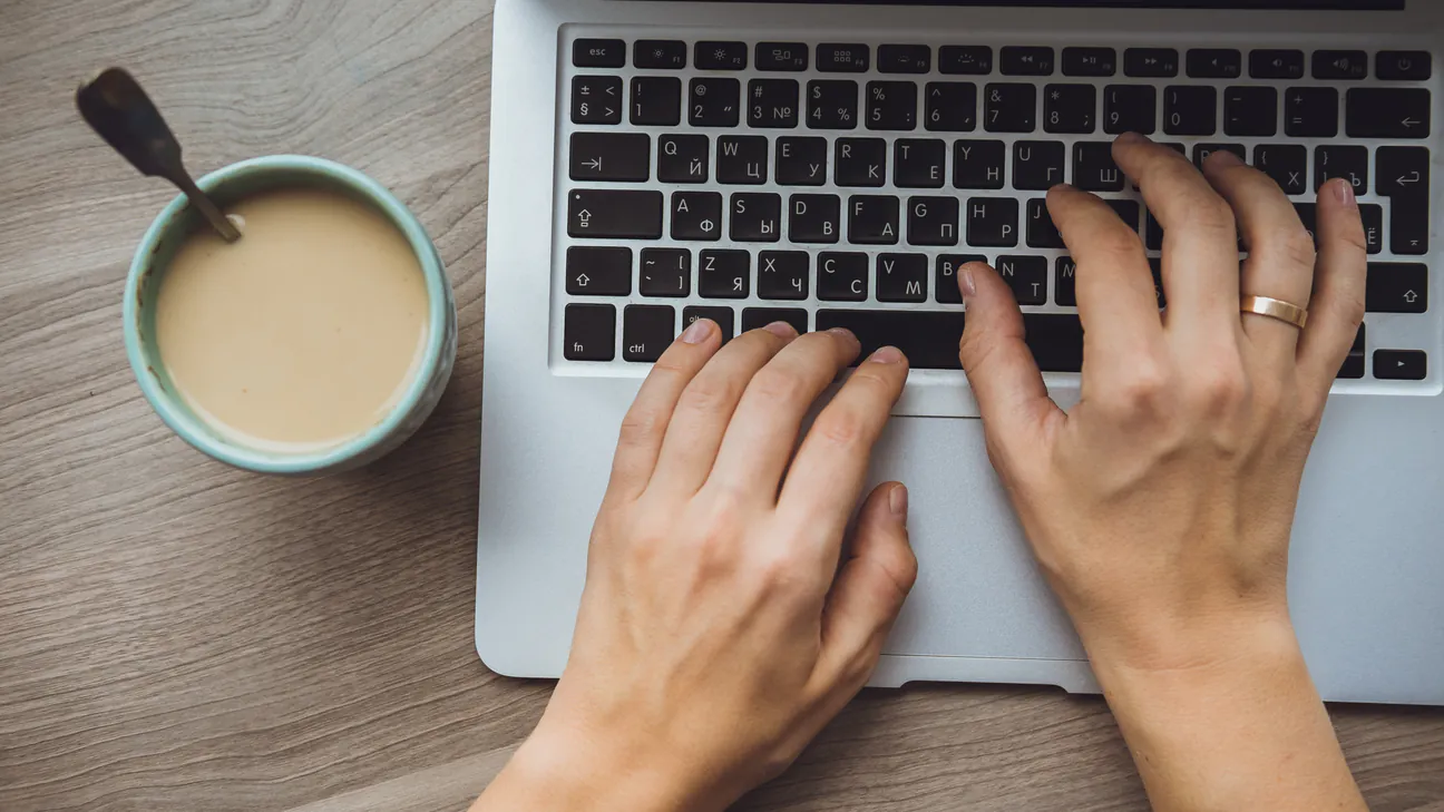Typing a blog article on a laptop with coffee nearby